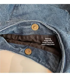 Detailaufnahme der starken Magnetverschlüsse aus Bronze auf blauem Denim-Stoffbeutel