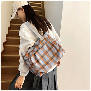 Detail of checkered canvas tote bag with drawstring design and grey ribbon handles