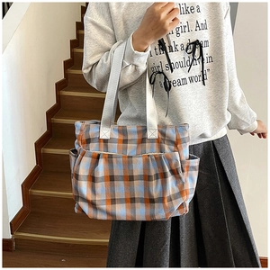 Detail view of large checkered tote bag showing multi-pocket structure and canvas texture