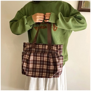 Detail of checkered canvas tote bag with side pockets and sturdy brown handles