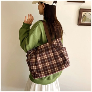 Detail of checkered canvas tote bag with brown straps and side pocket for practical use