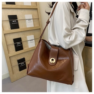 Close-up of brown faux leather tote bag with a round gold metallic twist lock closure