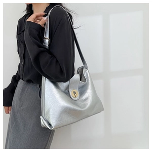 Chic silver tote bag with gold circular twist lock worn with a grey skirt