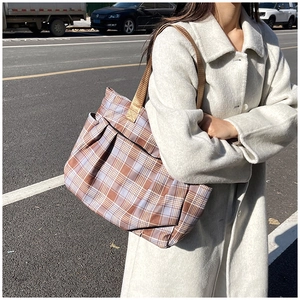 Macro shot of plaid tote bag featuring a side pocket and durable brown nylon handles