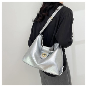Detail of silver metallic tote bag with mirror finish and gold circular buckle on shoulder