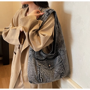 Nahaufnahme einer großen, grau gewaschenen Denim-Hobo-Tasche mit Fronttasche und Knopf