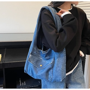 Detail einer Vintage-Denim-Tragetasche mit Frontklappe und Metallknopf für Damen