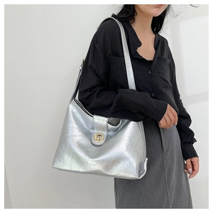 Detail of silver pleated leather tote with golden round buckle and soft shadow lighting