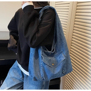 Detailansicht der großen Denim-Tragetasche mit Vordertasche und Metallknopf am Modell