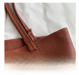 Macro shot of durable reinforced stitching on brown lychee texture leather tote bag