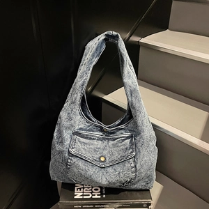 Detailaufnahme einer Vintage-Jeans-Hobo-Tasche mit Knopf-Vordertasche auf einem Buch