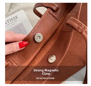Detail view of strong magnetic closure on brown litchi pattern leather tote bag