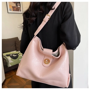 Pink leather hobo bag with gold circular lock detail shown on model in modern setting