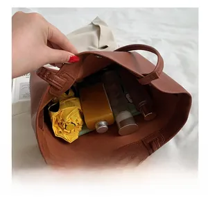 Top view showing large interior capacity of brown leather tote bag with umbrella and cosmetics