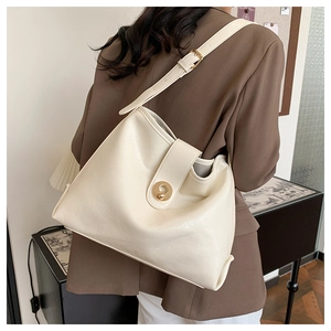 Detail of adjustable strap and golden round buckle on a cream leather tote bag