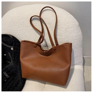Detail of a brown tote bag with premium pebble texture leather and thin shoulder straps