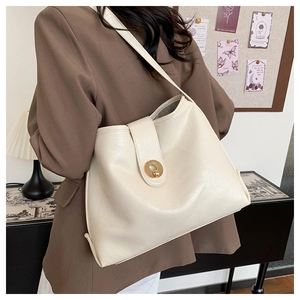 Detail of cream tote bag featuring premium leather texture and golden metal twist lock