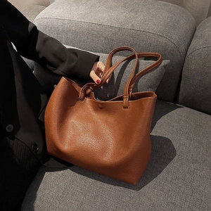 Detailed macro view of caramel lychee grain leather tote bag with sturdy shoulder straps