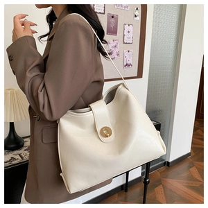 Detail of cream-white leather tote bag with elegant gold round twist lock closure