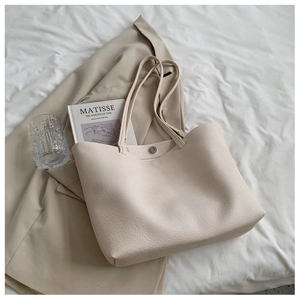 Top view of cream tote bag with litchi grain texture on elegant aesthetic background