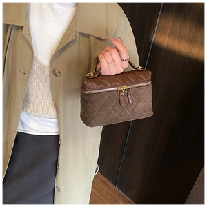 Détail du sac boîte matelassé marron foncé en daim avec fermetures éclair dorées