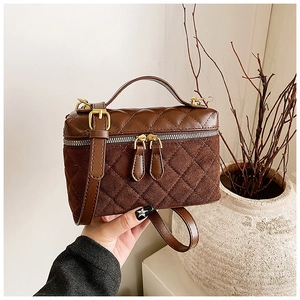 Détail du sac bandoulière matelassé marron avec fermetures dorées et texture daim