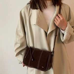 Brown faux suede crossbody bag with contrast stitching and drawstring detail on model