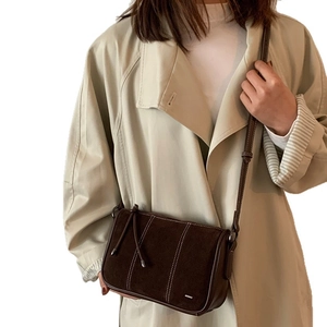 Large dark brown suede crossbody bag with decorative white stitching and long tassels