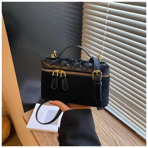 Détail du sac à bandoulière noir matelassé avec finitions dorées et surpiqûres élégantes