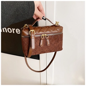 Détail du sac vanité matelassé marron avec finitions dorées et bandoulière réglable