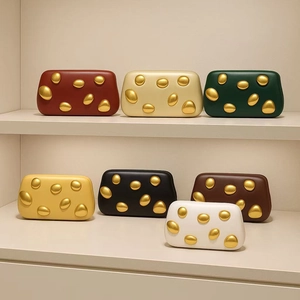 Row of colorful leather clutch bags with organic gold metal hardware on cream shelves