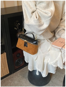 Détail du sac boîte en cuir matelassé avec coutures contrastées et fermetures éclair dorées
