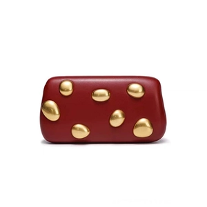 Close-up of wine red matte clutch featuring artistic golden pebble-shaped ornaments