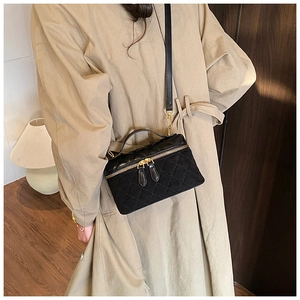 Détail d'un sac boîte matelassé noir avec double fermeture éclair dorée et poignée