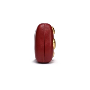 Side view of dark red leather evening clutch with three gold-tone metallic stud details