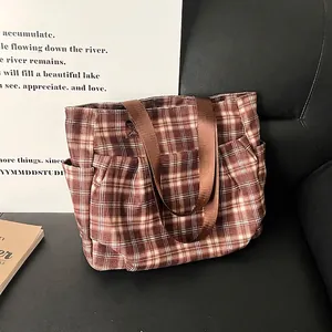 Brown plaid canvas tote bag with large capacity on a leather sofa in lifestyle setting