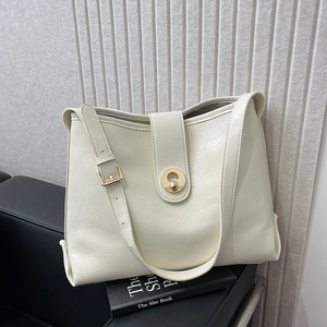 Elegant beige PU leather tote bag with gold buckle on black chair, minimalist shoulder bag