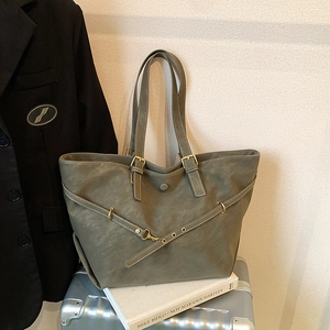 Minimalist grey-green large capacity tote bag with leather straps on a travel suitcase