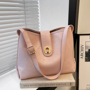 Pink faux leather tote bag with lychee texture and golden circular lock on a white table