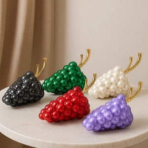Detailed close-up of grape-shaped clutch bags in five colors on marble background
