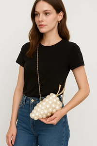 Detail of creative grape-shaped evening clutch made of cream faux pearls with gold chain