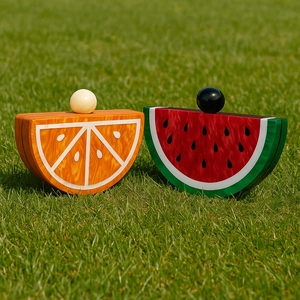 Detail of acrylic watermelon and orange fruit shaped clutches on green grass