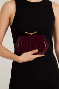 Close-up of wine red crocodile embossed hexagon clutch with elegant gold metal clasp