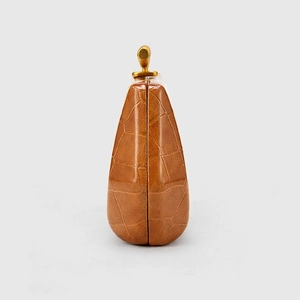 Detail view of brown crocodile texture handbag with gold metal lock and side triangle shape