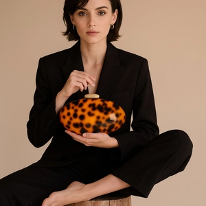 Chic acrylic evening clutch bag with tortoise shell pattern held by a model in a suit