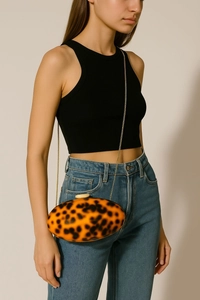 Detail of acrylic evening clutch featuring orange tortoiseshell pattern and gold chain strap