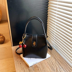 Classic black leather bucket bag with gold clasp and cute red cherry charm detail