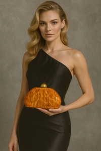 Detail of amber acrylic clutch shell with marble texture and golden ball clasp