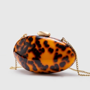 Detailed macro view of an oval acrylic evening bag with a leopard print and gold chain