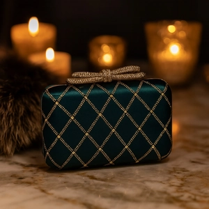 Detail of emerald green satin clutch with gold lattice pattern and crystal bow clasp